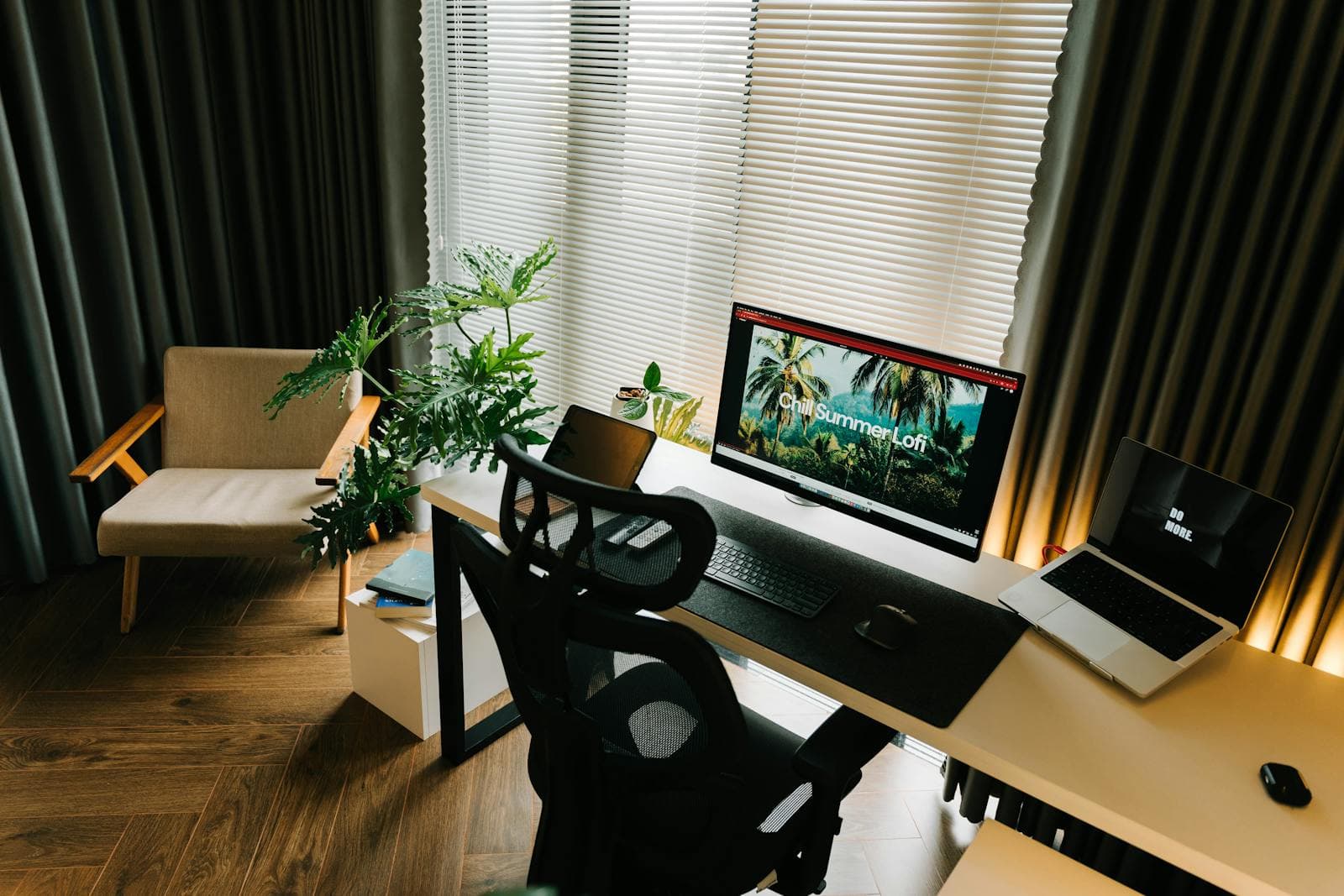 Estação de trabalho em casa com monitor, notebook de apoio e cadeira com encosto