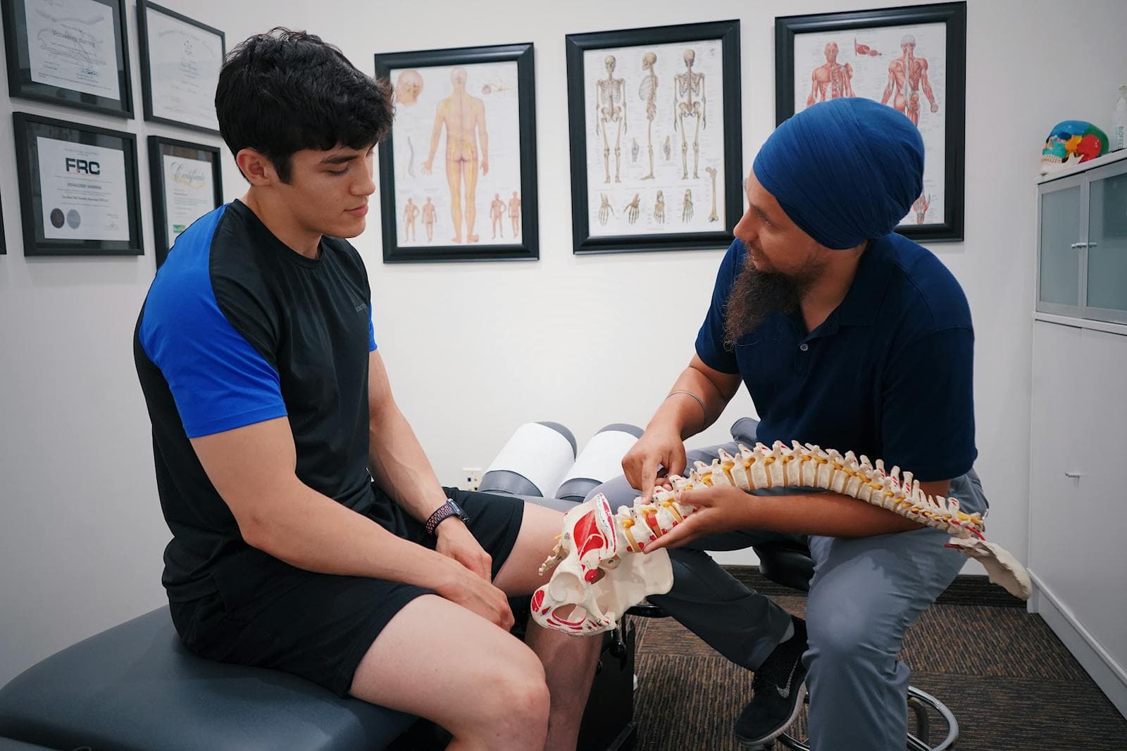 Fisioterapeuta explicando a anatomia da coluna vertebral com modelo didático
